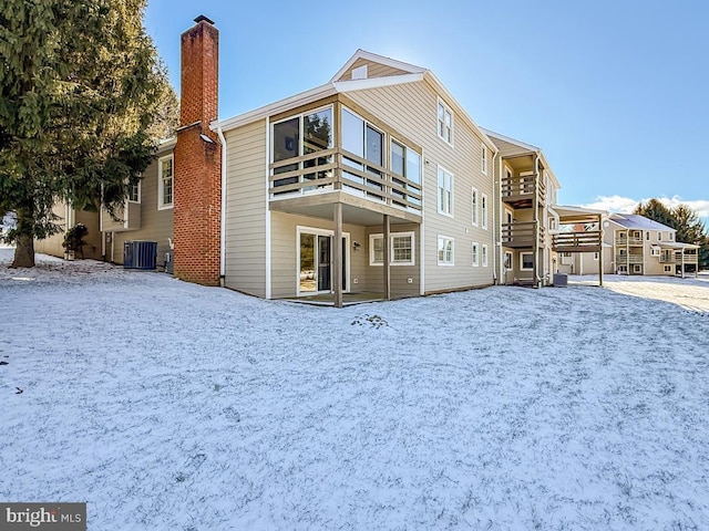 snow covered property with central AC