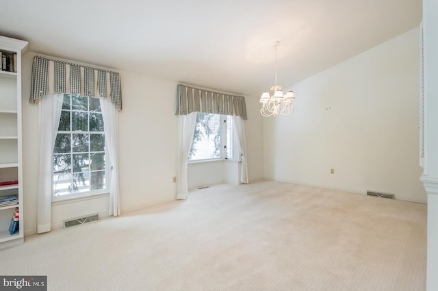 carpeted spare room featuring a chandelier