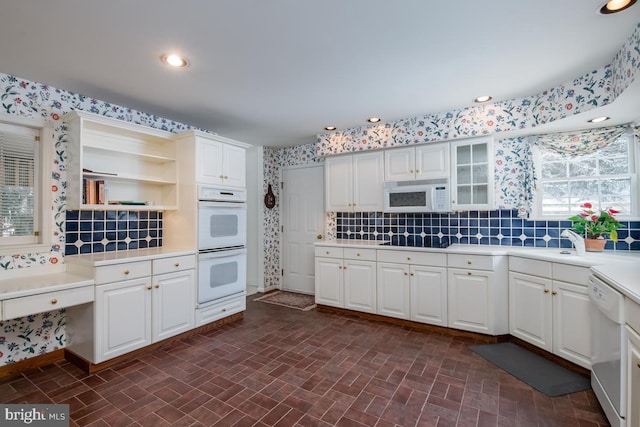 kitchen featuring backsplash, sink, white cabinets, and white appliances