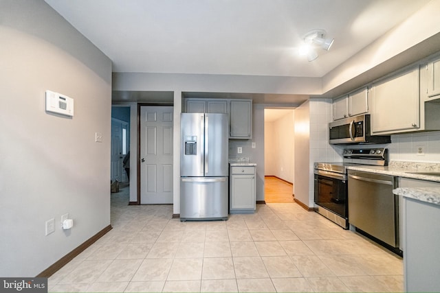 kitchen featuring tasteful backsplash, gray cabinetry, light tile patterned flooring, and appliances with stainless steel finishes