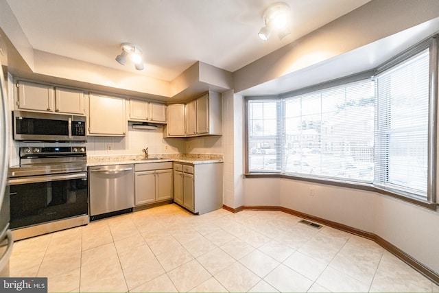 kitchen with decorative backsplash, appliances with stainless steel finishes, light tile patterned floors, and sink