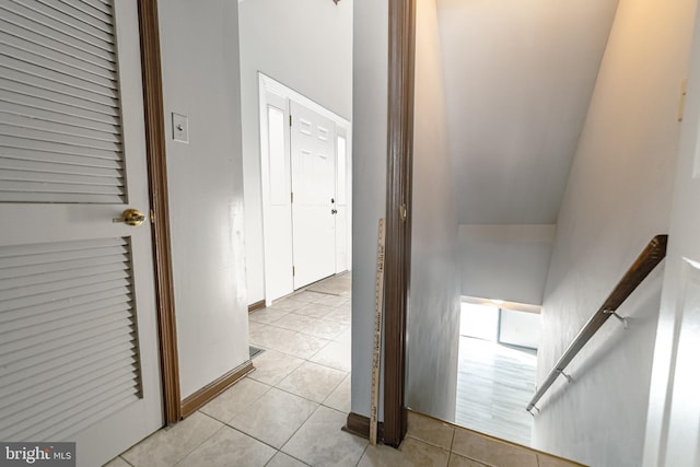 corridor with light tile patterned floors and vaulted ceiling