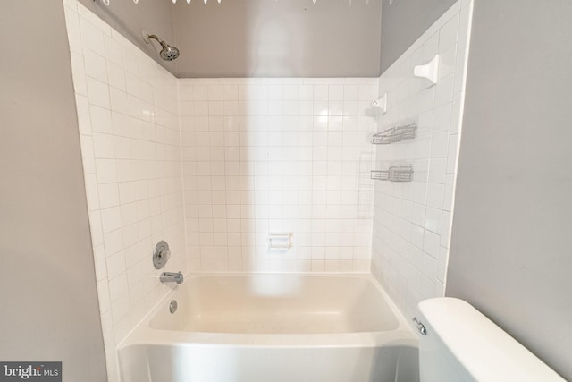 bathroom featuring tiled shower / bath combo and toilet