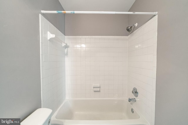 bathroom featuring tiled shower / bath combo and toilet