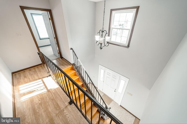 stairs with hardwood / wood-style flooring, a wealth of natural light, and an inviting chandelier