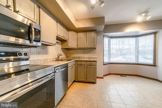 kitchen featuring light stone countertops, sink, stainless steel appliances, light brown cabinetry, and light tile patterned floors