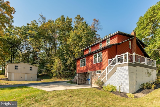 view of home's exterior featuring a lawn, an outdoor structure, and a deck