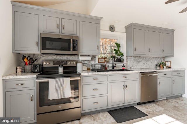 kitchen with sink, decorative backsplash, gray cabinets, ceiling fan, and stainless steel appliances