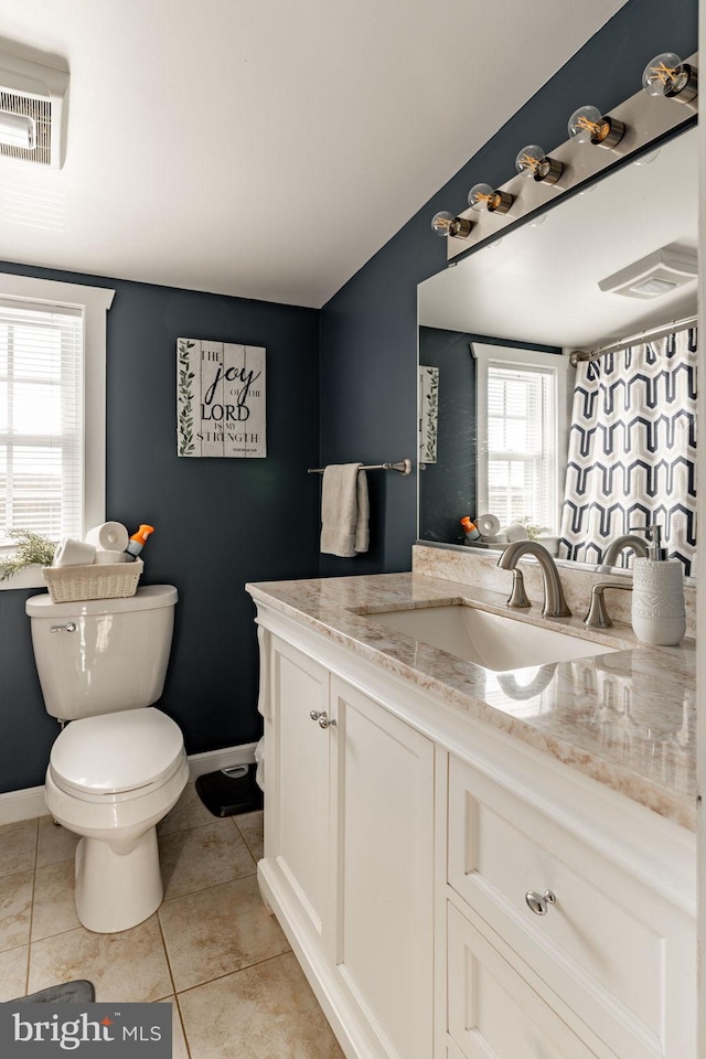 bathroom with tile patterned floors, a wealth of natural light, vanity, and toilet