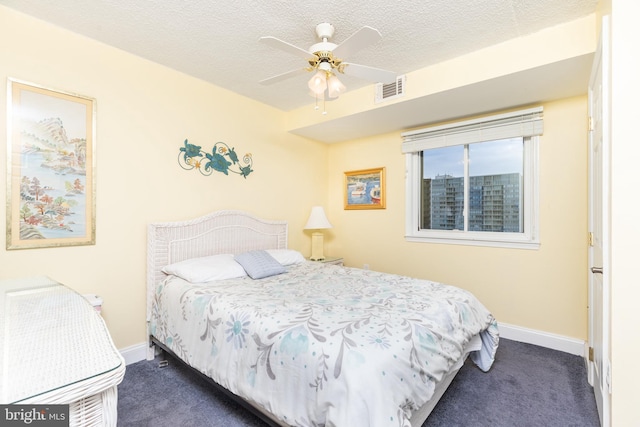 bedroom featuring ceiling fan, a textured ceiling, and dark colored carpet