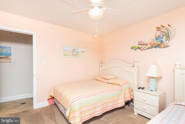 bedroom with ceiling fan, light colored carpet, and a textured ceiling