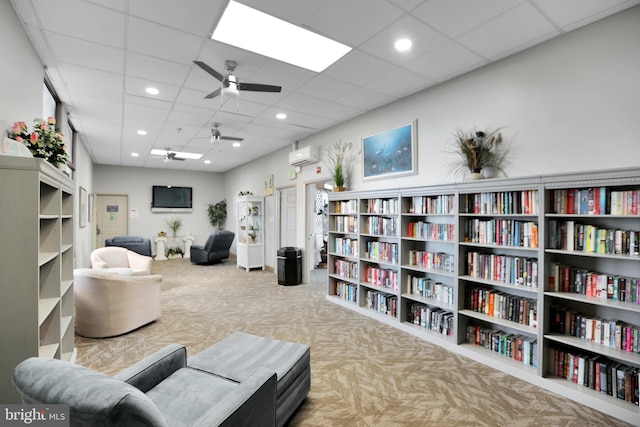 living area featuring a paneled ceiling, carpet flooring, ceiling fan, and a wall mounted air conditioner