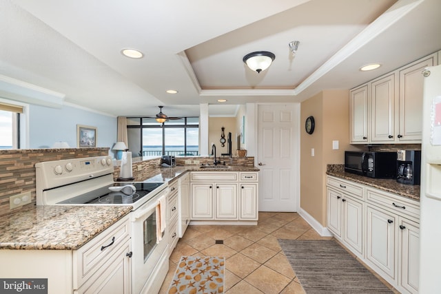 kitchen with decorative backsplash, sink, white appliances, and kitchen peninsula