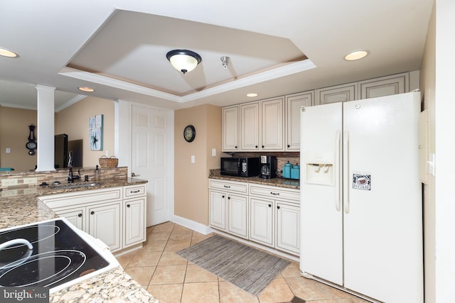 kitchen featuring tasteful backsplash, white refrigerator with ice dispenser, ornamental molding, and a tray ceiling