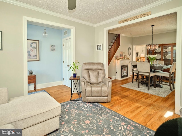 living room featuring ceiling fan with notable chandelier, a textured ceiling, hardwood / wood-style flooring, and crown molding