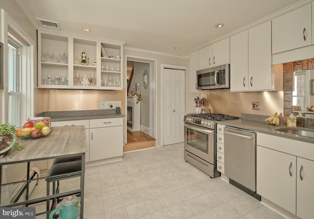 kitchen featuring visible vents, open shelves, a sink, stainless steel appliances, and crown molding