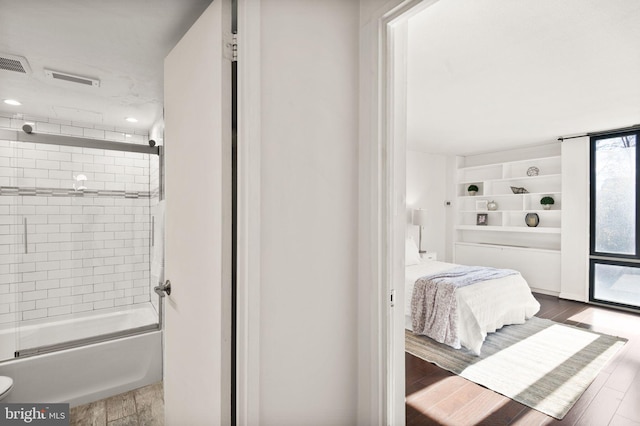 bathroom featuring hardwood / wood-style floors and combined bath / shower with glass door