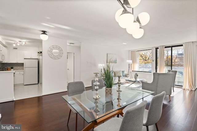 dining space with a chandelier, expansive windows, and dark wood-type flooring