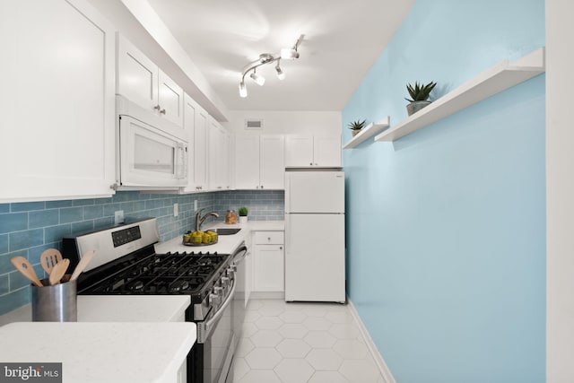 kitchen with tasteful backsplash, white appliances, sink, light tile patterned floors, and white cabinetry