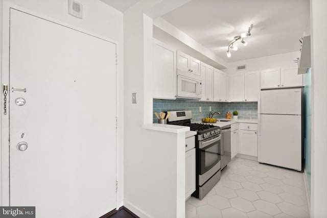 kitchen with white cabinets, sink, decorative backsplash, light tile patterned floors, and stainless steel appliances