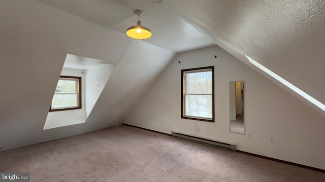 additional living space featuring lofted ceiling with skylight, a textured ceiling, light carpet, and a baseboard heating unit