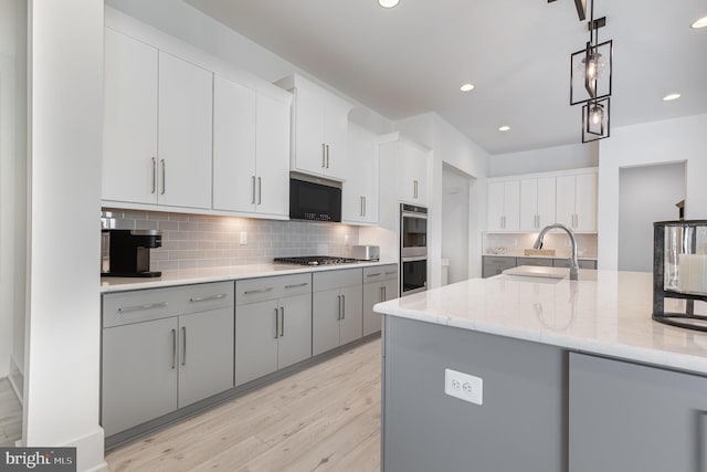 kitchen with sink, decorative backsplash, appliances with stainless steel finishes, decorative light fixtures, and light stone counters