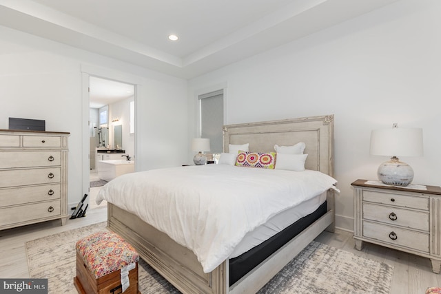 bedroom featuring connected bathroom and light hardwood / wood-style flooring