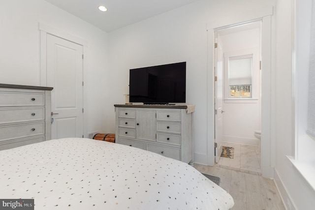 bedroom with light hardwood / wood-style floors and connected bathroom