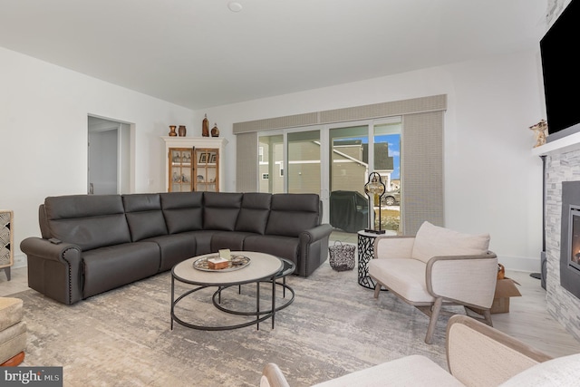 living room with a stone fireplace and light wood-type flooring