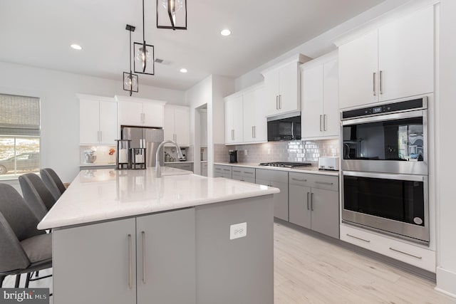 kitchen with a large island, a kitchen bar, hanging light fixtures, and appliances with stainless steel finishes