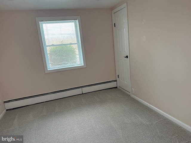 carpeted empty room featuring a baseboard heating unit