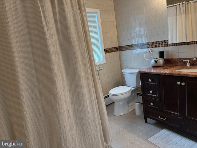 bathroom featuring baseboard heating, tile patterned flooring, toilet, vanity, and tile walls