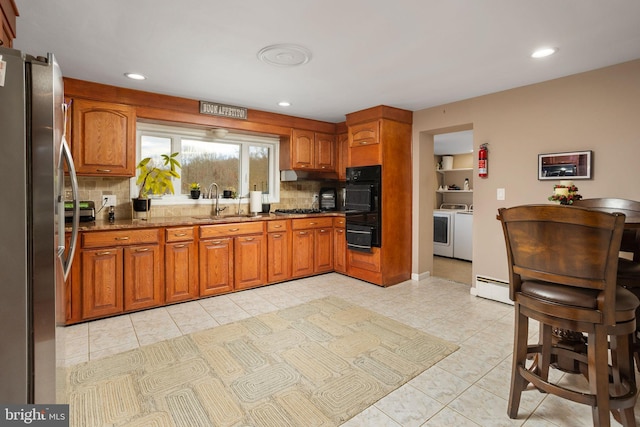 kitchen with decorative backsplash, stainless steel fridge, sink, stone countertops, and washing machine and dryer