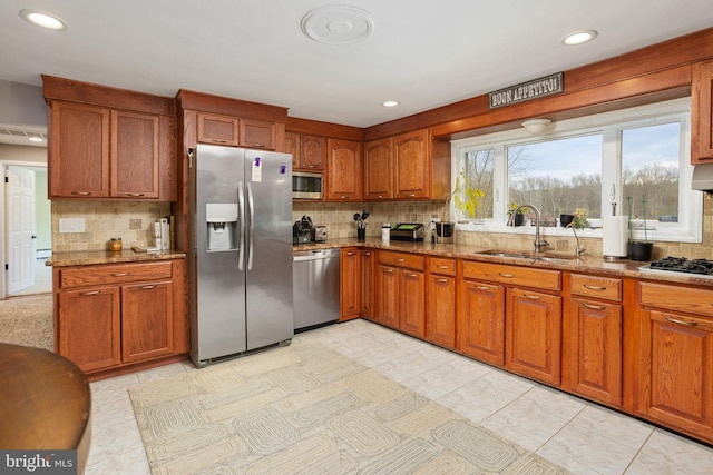 kitchen with light stone countertops, sink, backsplash, light tile patterned flooring, and appliances with stainless steel finishes