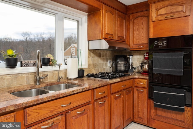 kitchen with black appliances, light stone countertops, sink, and tasteful backsplash