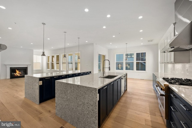 kitchen with decorative light fixtures, high end stainless steel range oven, a spacious island, and sink