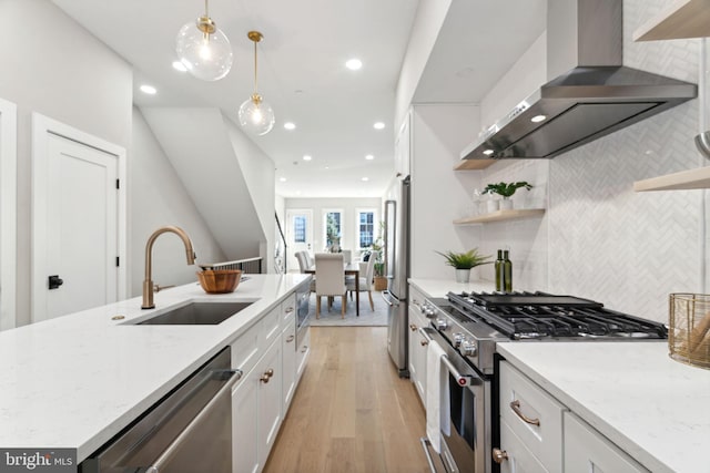 kitchen featuring white cabinetry, pendant lighting, stainless steel appliances, and wall chimney range hood