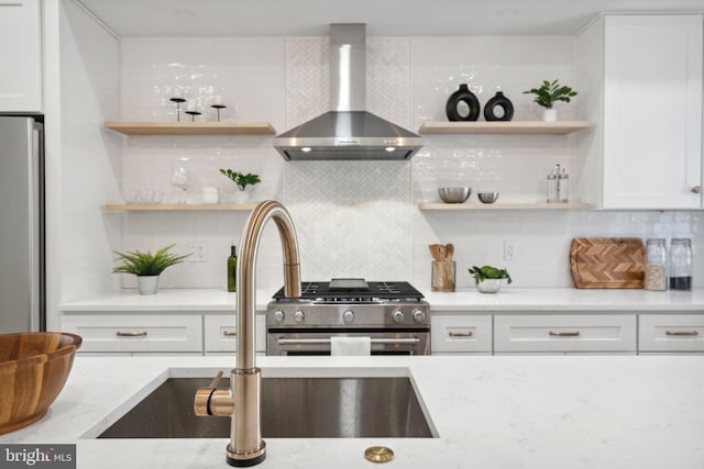 kitchen featuring white cabinets, decorative backsplash, wall chimney exhaust hood, and high end stainless steel range oven