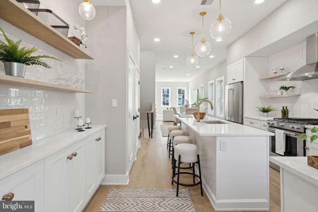 kitchen featuring high quality appliances, backsplash, a kitchen breakfast bar, an island with sink, and white cabinetry