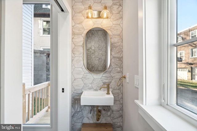 bathroom featuring plenty of natural light, sink, and tile walls