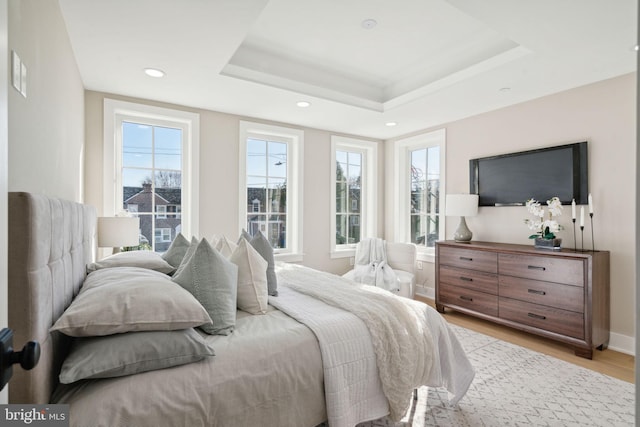 bedroom with a tray ceiling and light hardwood / wood-style floors