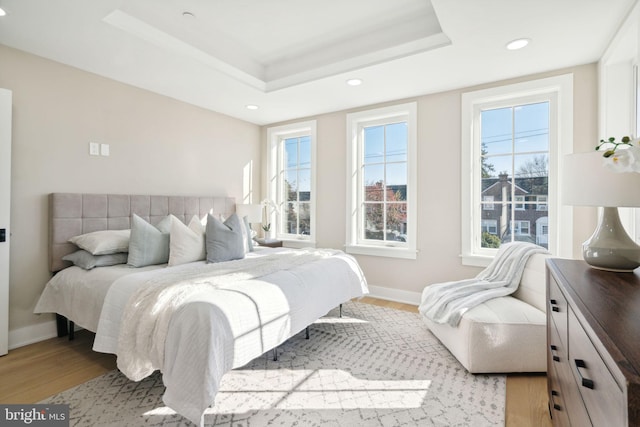 bedroom featuring a tray ceiling and light hardwood / wood-style flooring