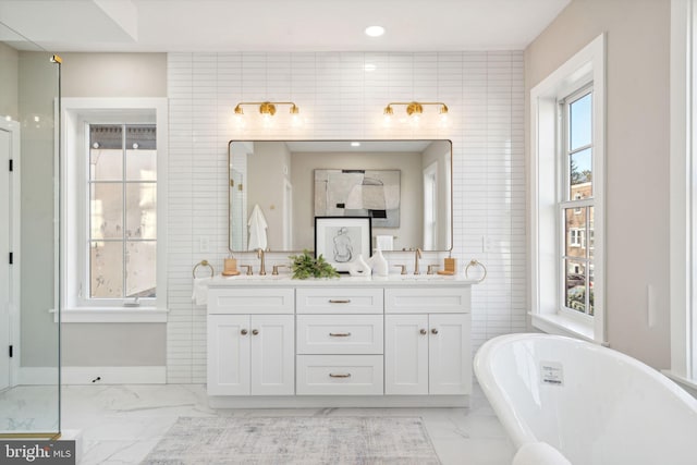 bathroom featuring vanity, tile walls, a wealth of natural light, and a tub