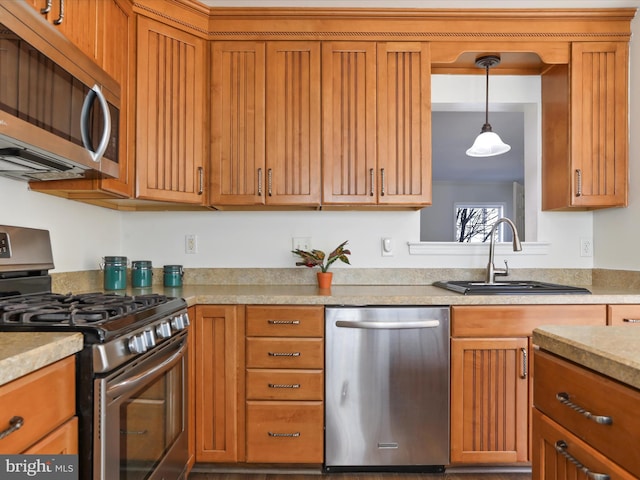 kitchen with appliances with stainless steel finishes, brown cabinets, light countertops, and a sink