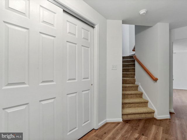 staircase featuring baseboards and wood finished floors