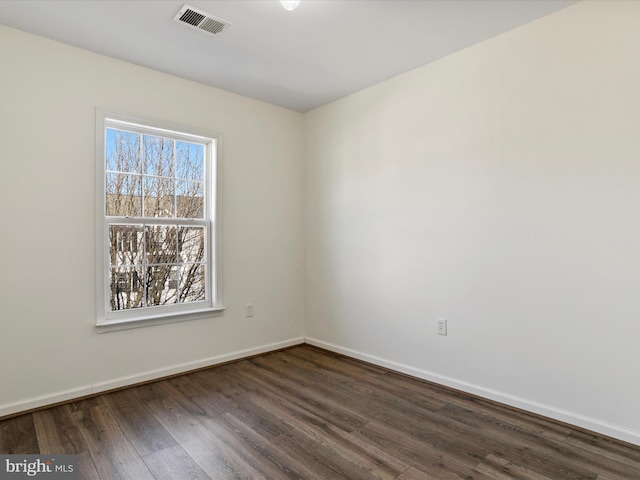 spare room with visible vents, baseboards, and dark wood-type flooring