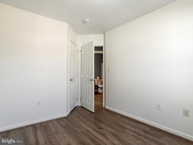 unfurnished bedroom with baseboards and dark wood-style flooring