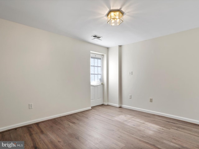 empty room with visible vents, baseboards, and wood finished floors