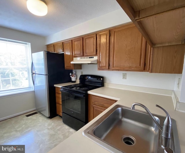 kitchen with stainless steel refrigerator, black range with electric stovetop, and sink