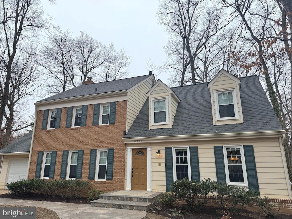 view of front of house featuring an attached garage, brick siding, and roof with shingles